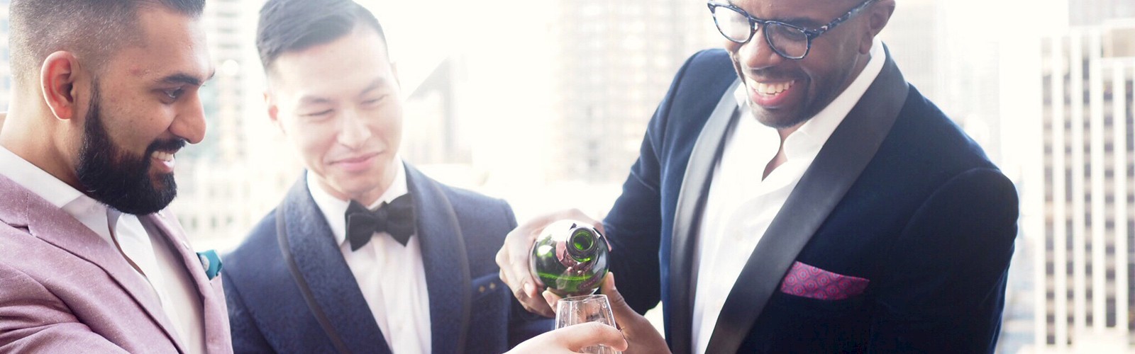 A group of well-dressed men stands on a balcony, smiling and pouring drinks while enjoying a gathering or celebration.