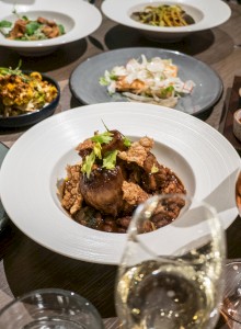 A table with various gourmet dishes, including meats and salads, along with filled wine glasses, suggesting a fine dining experience.