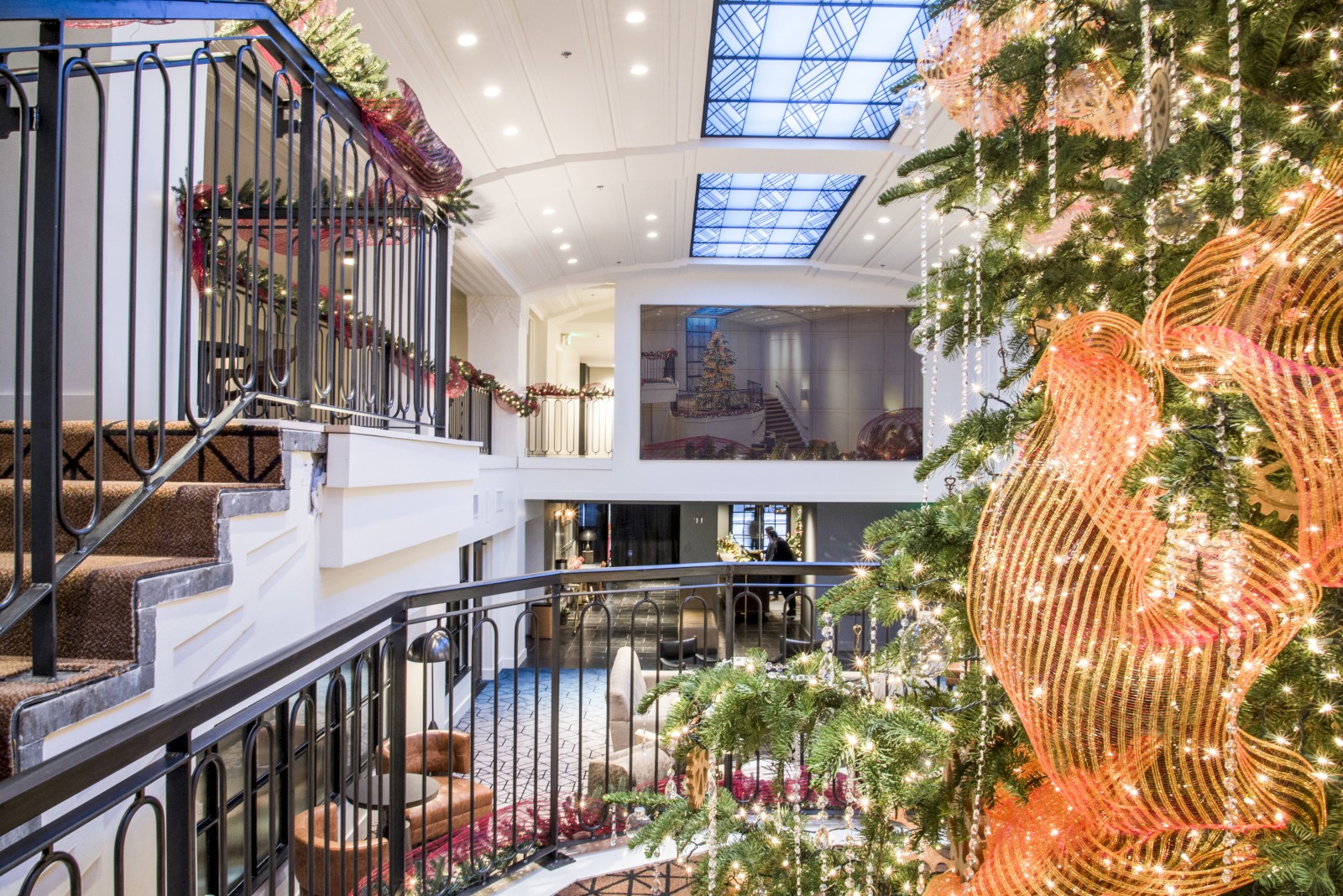 A decorated indoor space with a Christmas tree, festive lights, and elegant railing, creating a warm holiday atmosphere.