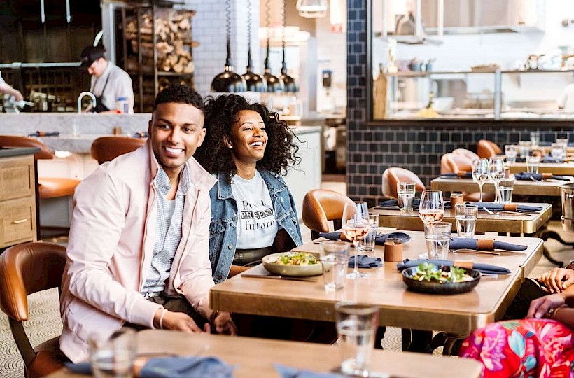 Two people are sitting in a restaurant dining area, enjoying a meal.